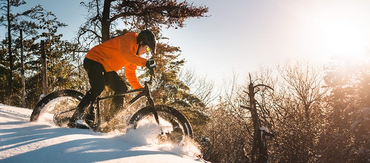 Un homme sur un fat bike roulant dans la neige poudreuse