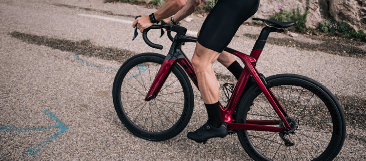 Un cycliste debout sur un vélo de route aéro Trek Madone rouge et noir